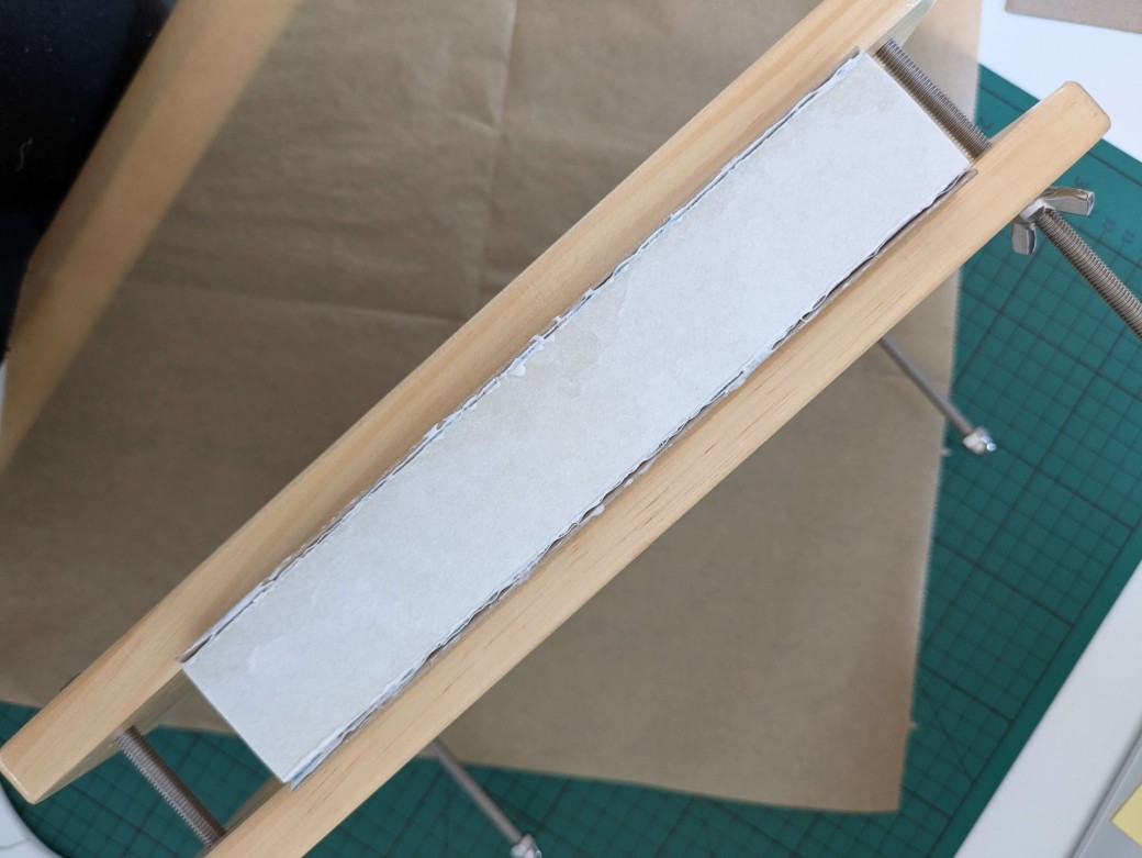 A textblock inserted inside a book press, with the empty spine showing face up.