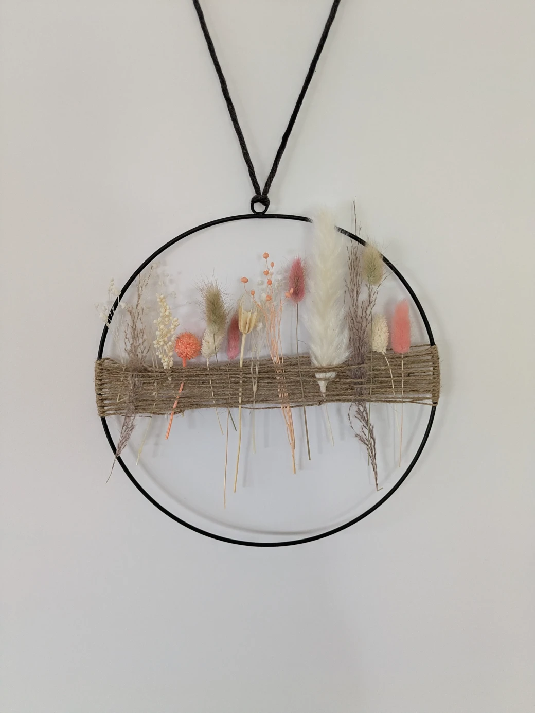 A metal ring with cord tied between both sides and dried flowers woven in 